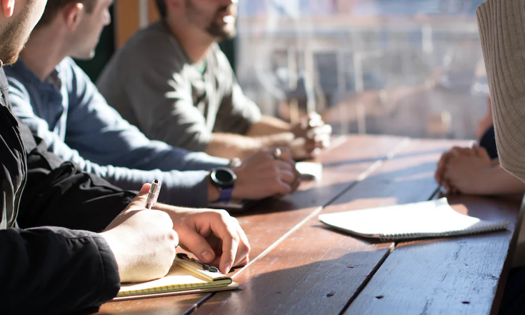 People sitting at a table with pen and paper